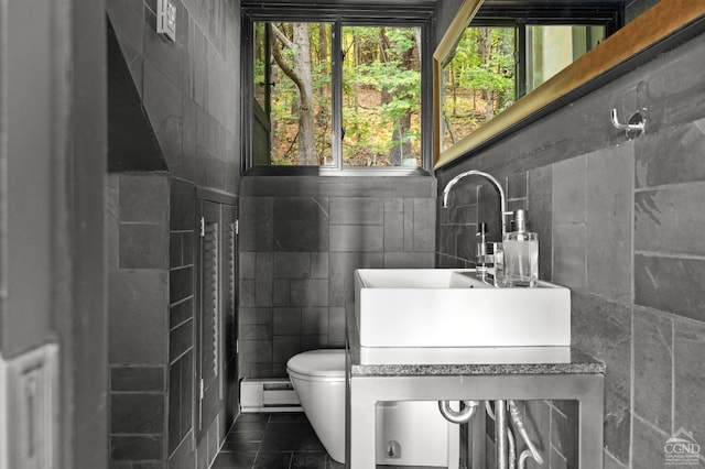 bathroom with tile patterned flooring, toilet, tile walls, and a wealth of natural light