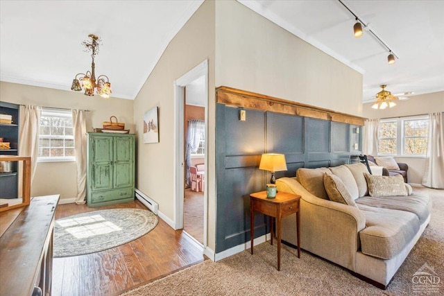 living area featuring a healthy amount of sunlight, wood finished floors, a baseboard heating unit, and vaulted ceiling