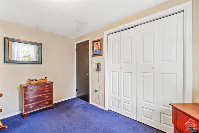 bedroom featuring a closet, baseboards, and dark colored carpet