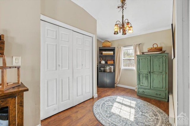 foyer entrance with crown molding, a notable chandelier, wood finished floors, and baseboards