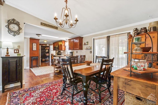 dining area with baseboards, dark wood-type flooring, an inviting chandelier, and crown molding