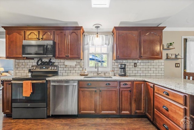 kitchen with light stone countertops, a sink, decorative backsplash, stainless steel appliances, and crown molding