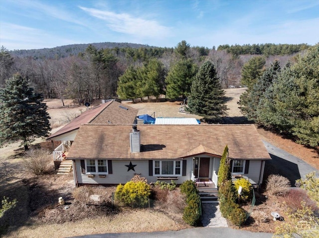 view of front of home with a view of trees and a chimney