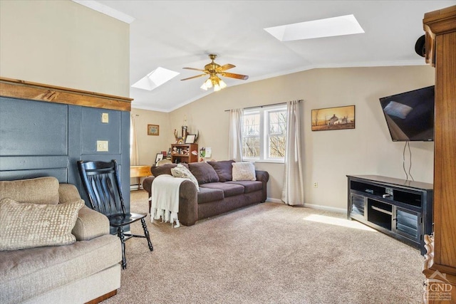 carpeted living area featuring ceiling fan, vaulted ceiling with skylight, baseboards, and ornamental molding