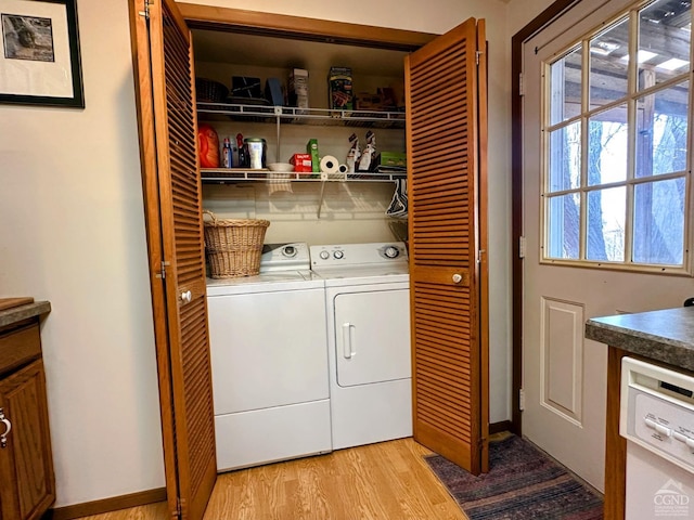 washroom featuring laundry area, baseboards, light wood-type flooring, and washer and clothes dryer