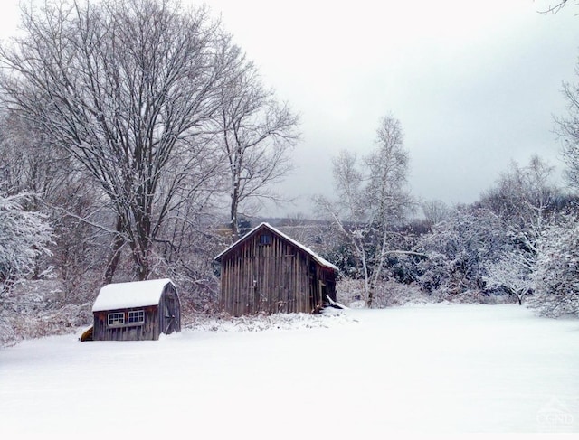 snow covered structure featuring an outdoor structure and a shed