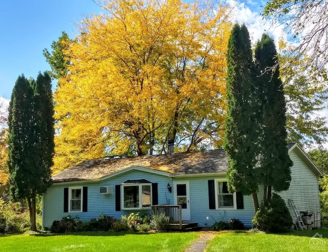 ranch-style home featuring a wall mounted air conditioner and a front yard