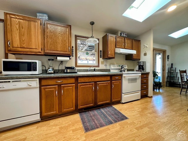 kitchen with under cabinet range hood, white appliances, brown cabinets, and a sink