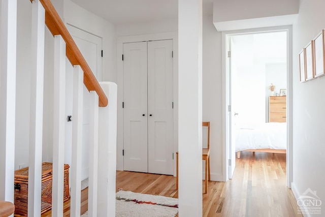 corridor featuring light wood finished floors and stairway