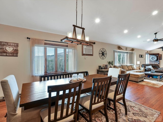 dining area with wood-type flooring, an AC wall unit, ceiling fan, and lofted ceiling