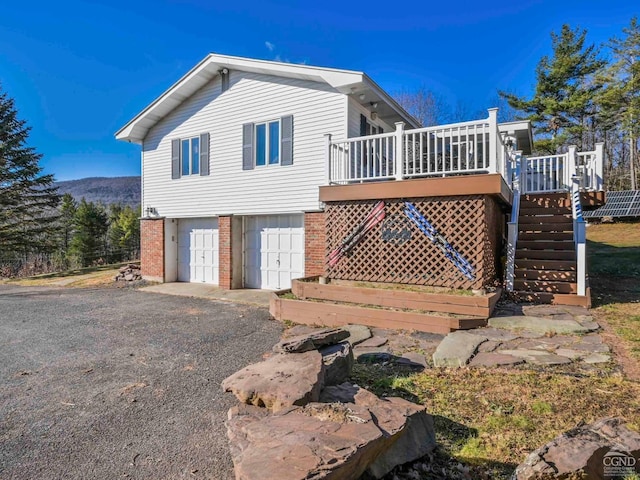 rear view of house featuring a garage and a wooden deck