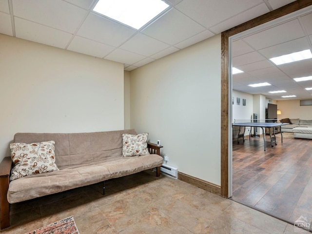 living room featuring a drop ceiling, a baseboard heating unit, and light hardwood / wood-style flooring