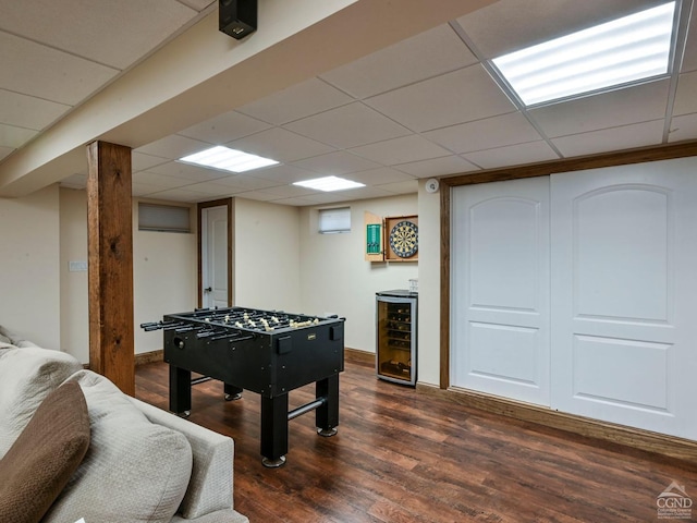 recreation room featuring wine cooler, a drop ceiling, and dark hardwood / wood-style floors