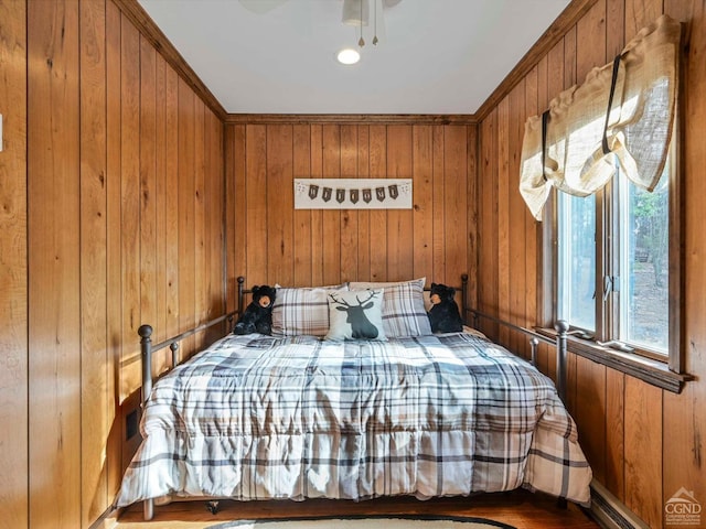 bedroom featuring ceiling fan, wooden walls, and crown molding