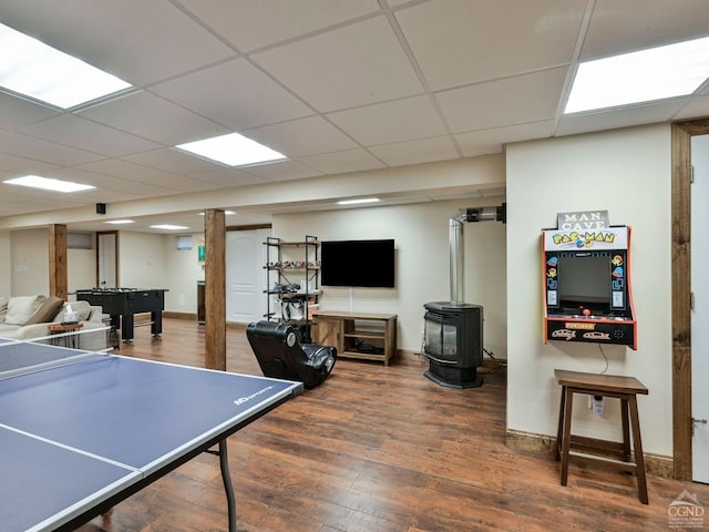 game room featuring a wood stove, a drop ceiling, and hardwood / wood-style flooring