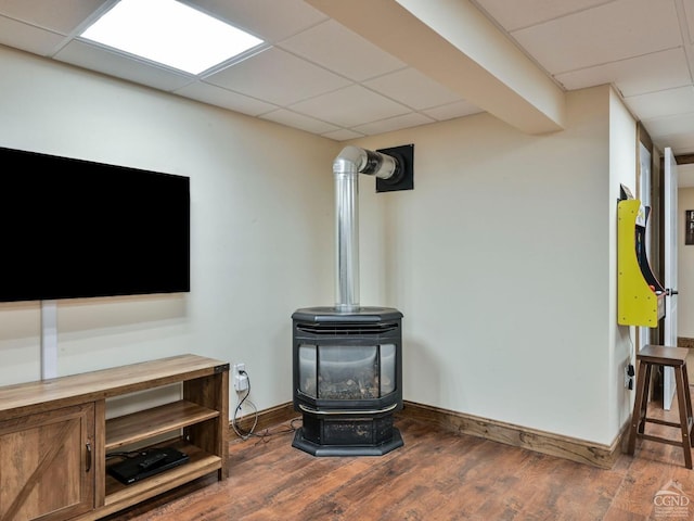 room details featuring hardwood / wood-style floors, a wood stove, and a drop ceiling