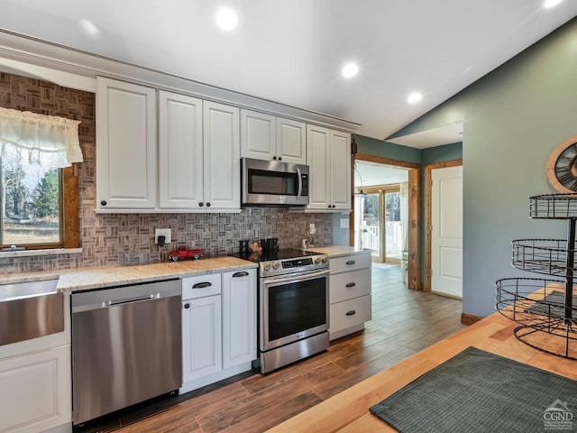 kitchen featuring lofted ceiling, white cabinets, dark hardwood / wood-style floors, appliances with stainless steel finishes, and tasteful backsplash