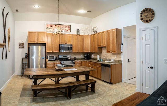 kitchen with hanging light fixtures, vaulted ceiling, light wood-type flooring, appliances with stainless steel finishes, and tasteful backsplash