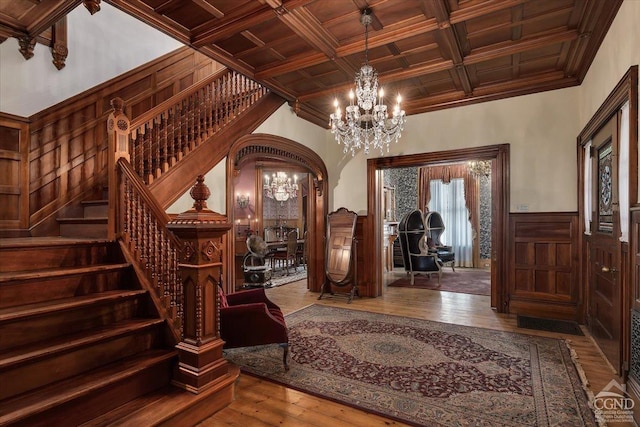 wine area featuring coffered ceiling, crown molding, wood-type flooring, beam ceiling, and a notable chandelier