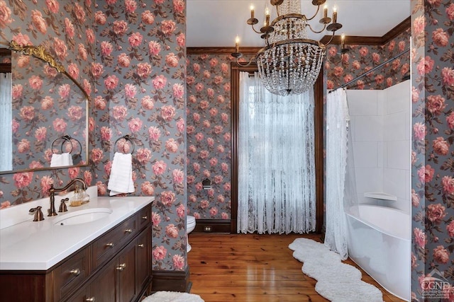 full bathroom with hardwood / wood-style floors, vanity, an inviting chandelier, toilet, and ornamental molding