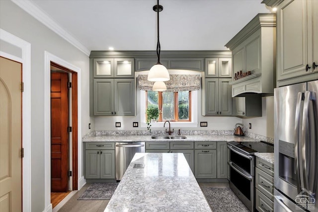 kitchen with appliances with stainless steel finishes, light stone counters, sink, decorative light fixtures, and hardwood / wood-style flooring