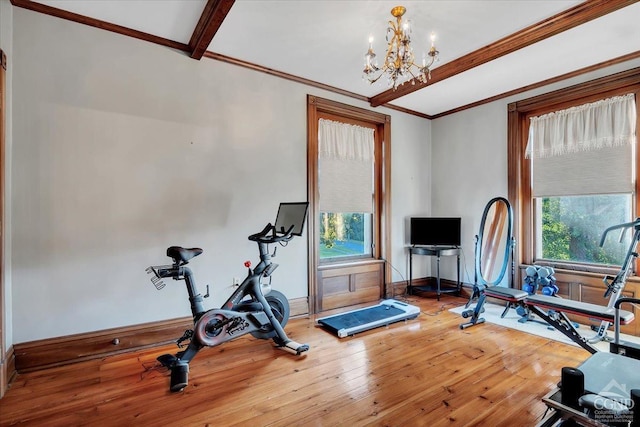 exercise area with hardwood / wood-style floors, a notable chandelier, and ornamental molding