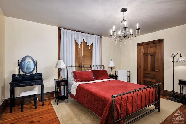 bedroom with hardwood / wood-style flooring and an inviting chandelier