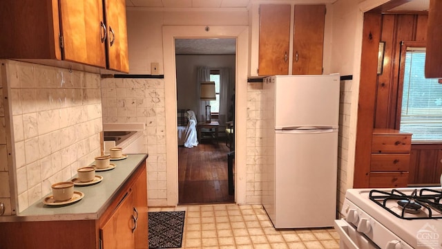 kitchen featuring backsplash, light hardwood / wood-style floors, and white appliances