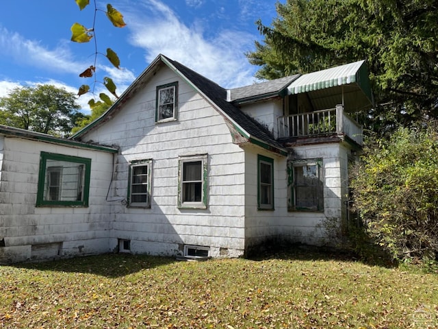 view of property exterior featuring a balcony and a lawn