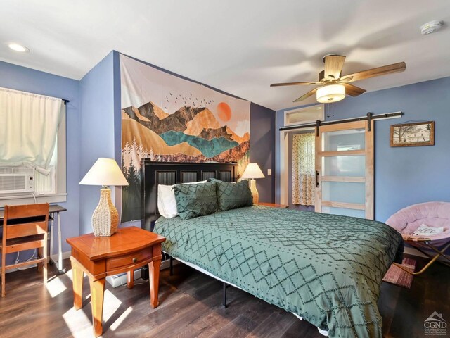 bedroom with ceiling fan, a barn door, wood-type flooring, and cooling unit