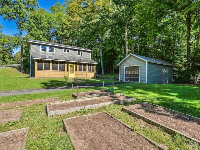 rear view of property featuring a lawn, a garage, and an outdoor structure