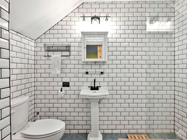 bathroom with toilet, lofted ceiling, and tile walls