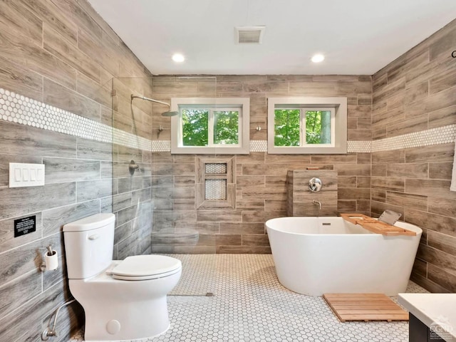 full bathroom featuring vanity, toilet, tile walls, and plus walk in shower