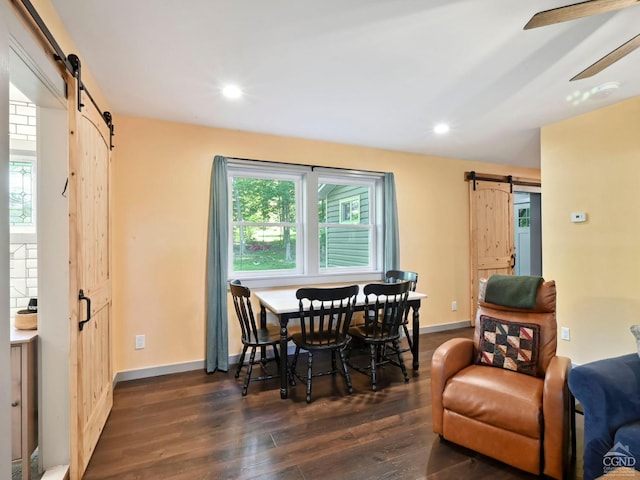 dining space with a barn door, ceiling fan, and dark wood-type flooring