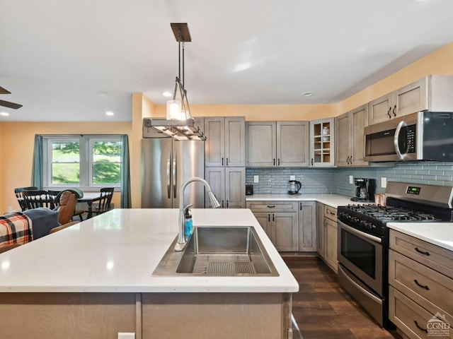 kitchen with dark wood-type flooring, stainless steel appliances, a center island with sink, and sink