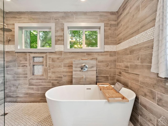 bathroom featuring plus walk in shower and tile walls