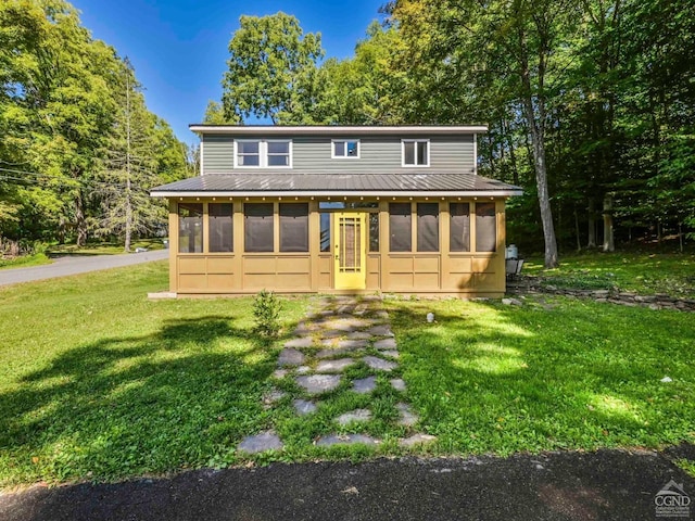 rear view of house with a sunroom and a lawn