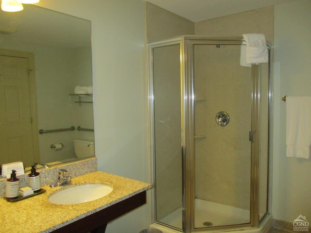 bathroom with vanity, a shower with shower door, and toilet