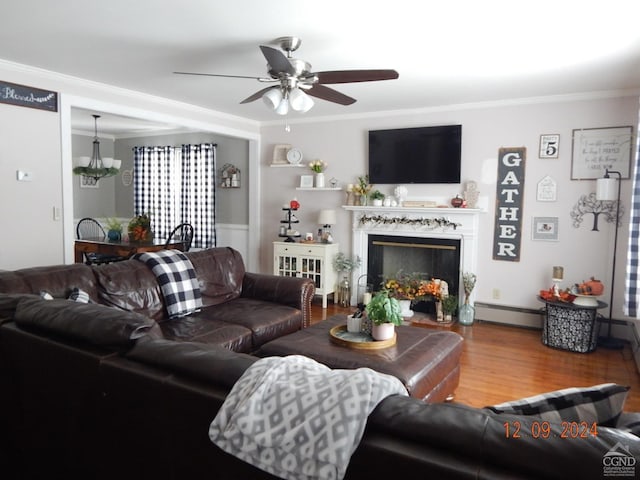 living room with ceiling fan, a baseboard radiator, a high end fireplace, crown molding, and wood-type flooring