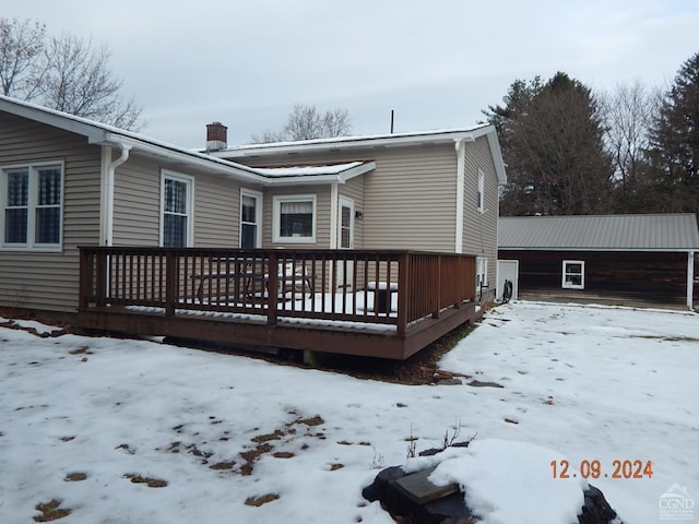 snow covered back of property with a deck