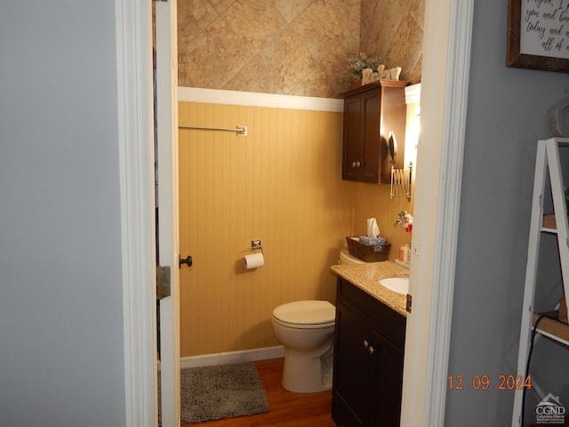 bathroom with wood walls, vanity, wood-type flooring, and toilet