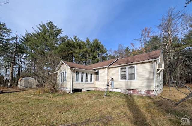 back of property featuring a storage unit and a lawn