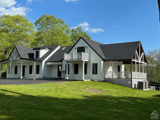 rear view of house featuring a porch, a balcony, a yard, and cooling unit