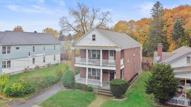 back of house featuring a lawn, a balcony, and covered porch