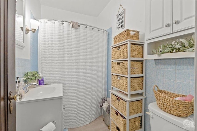 bathroom with vanity, toilet, and tile walls