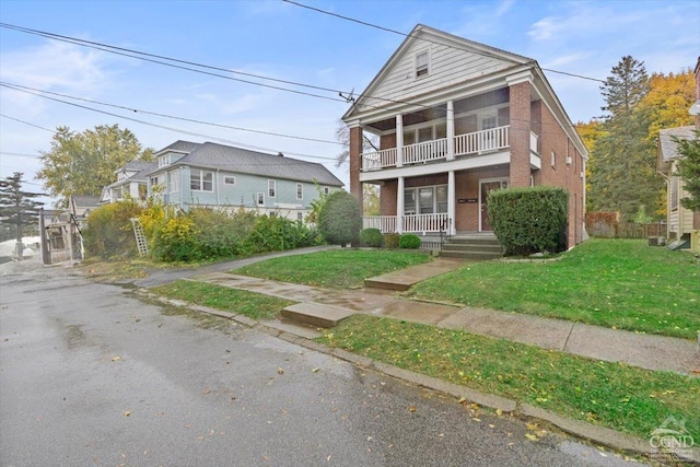 view of front facade featuring a porch, a balcony, and a front yard