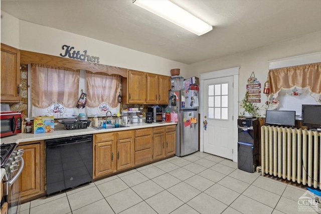 kitchen with light tile patterned flooring, radiator heating unit, sink, and black appliances