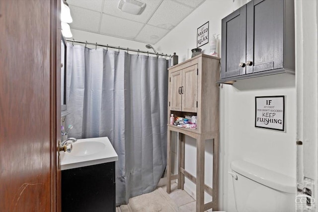 bathroom featuring a paneled ceiling, vanity, toilet, and tile patterned flooring