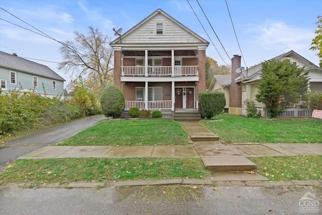 view of front of home with a porch, a balcony, and a front lawn