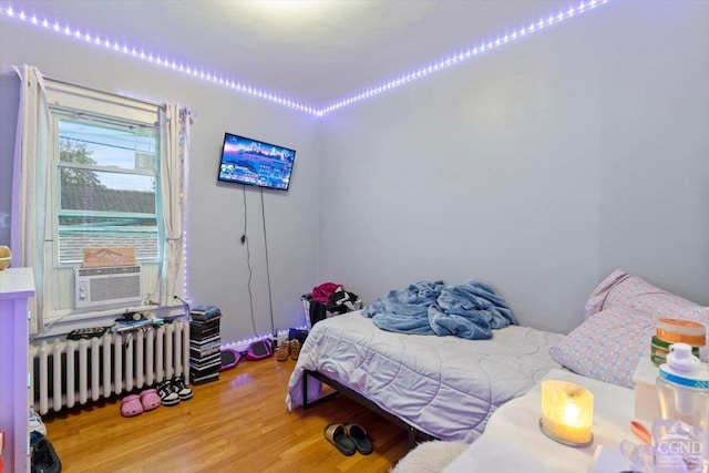 bedroom with radiator heating unit, cooling unit, and hardwood / wood-style floors